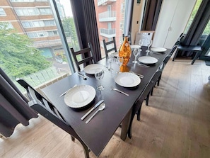 A dining table set with plates, cutlery, and glasses, with a view of buildings and greenery outside. - 3bdr + Balcony | London bridge, borough, the shard (London)
