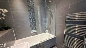 Un baño moderno con bañera, cabina de ducha de vidrio y un perchero para toallas.