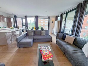 A modern living room with a grey sofa, a coffee table with a board game, and a kitchen area in the background. - 3bdr + Balcony | London bridge, borough, the shard (London)