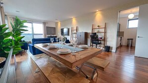 A dining area with a wooden table set for four, a blue sofa, and a TV in the background.