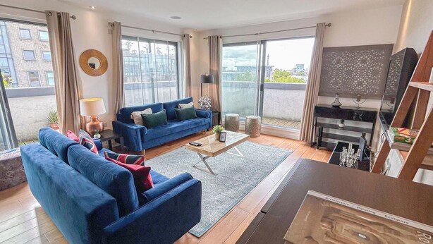 Ett modernt vardagsrum med en blå soffa, ett soffbord och en tv.