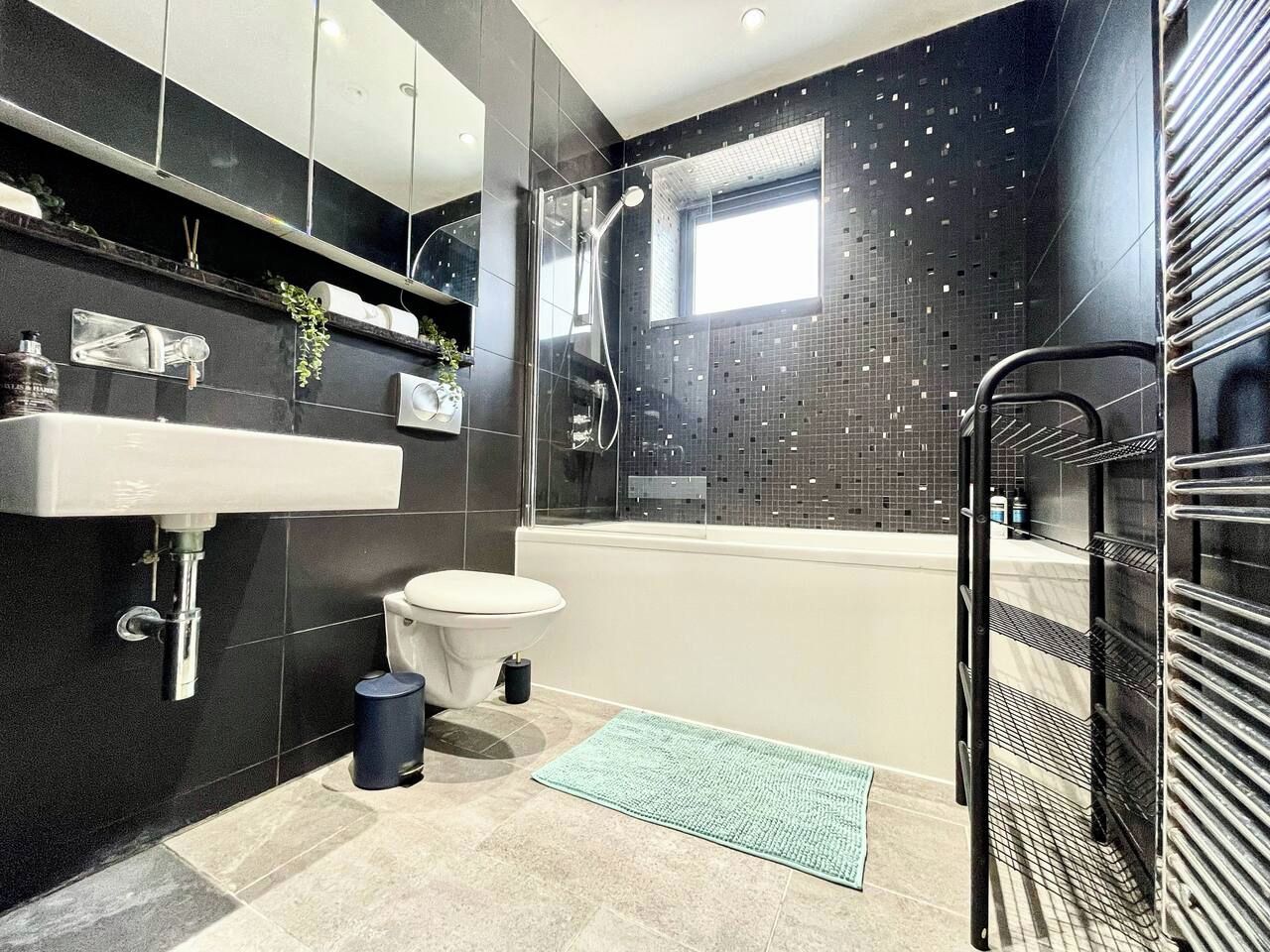 A modern bathroom with a bathtub, toilet, and shower.