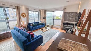 A modern living room with a blue sofa set, a coffee table, and a TV stand with books and decorative items.