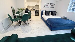 Une chambre d’hôtel de taille réduite comprenant un lit, un coin repas et une kitchenette.