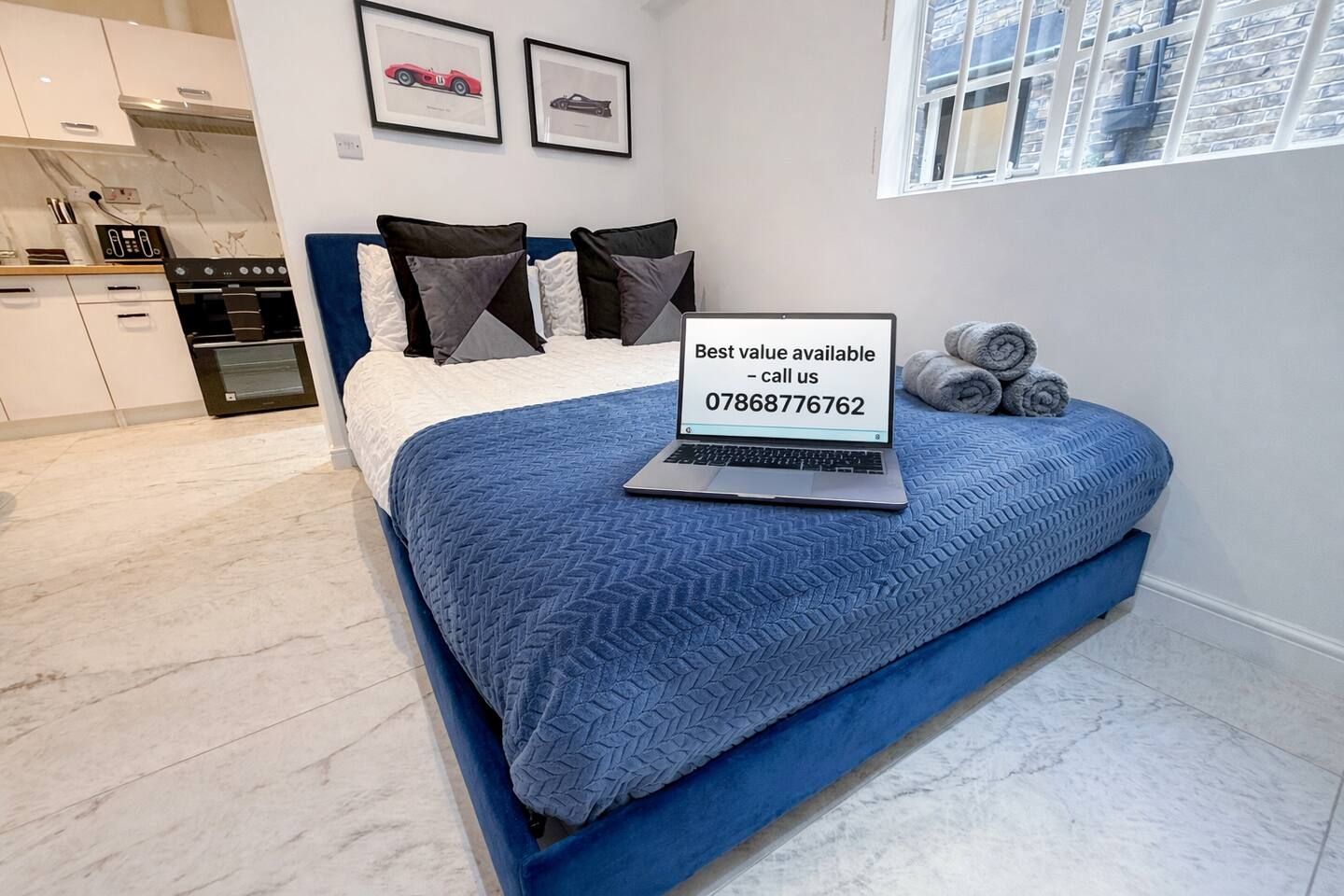 Un dormitorio con una cama, una computadora portátil y una ventana.