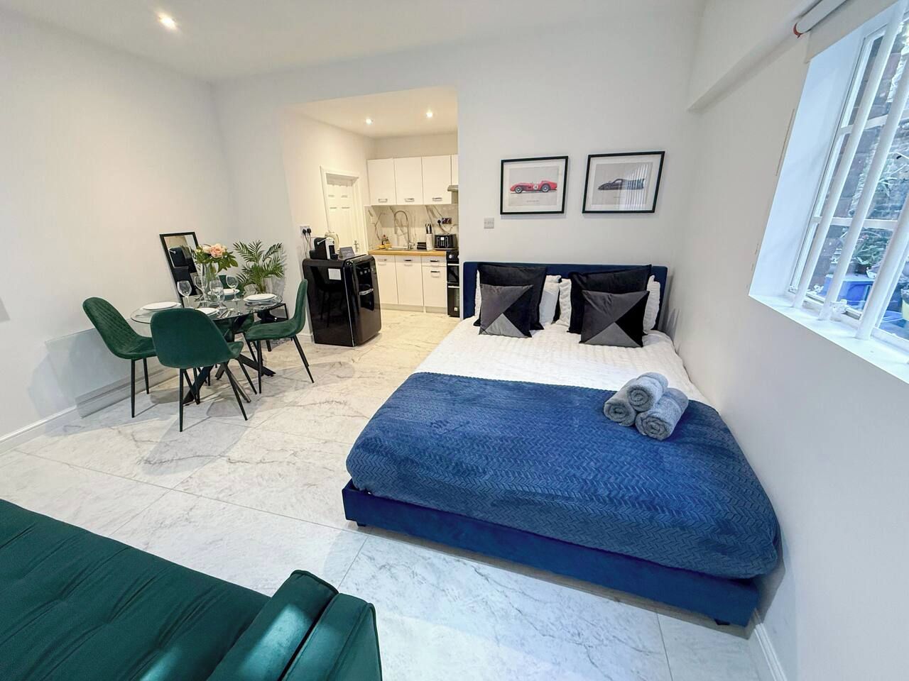 Une chambre à coucher moderne avec un lit, un coin repas et une cuisine en arrière-plan.