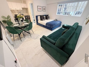 A compact living space with a dining area, a sofa, and a bed.