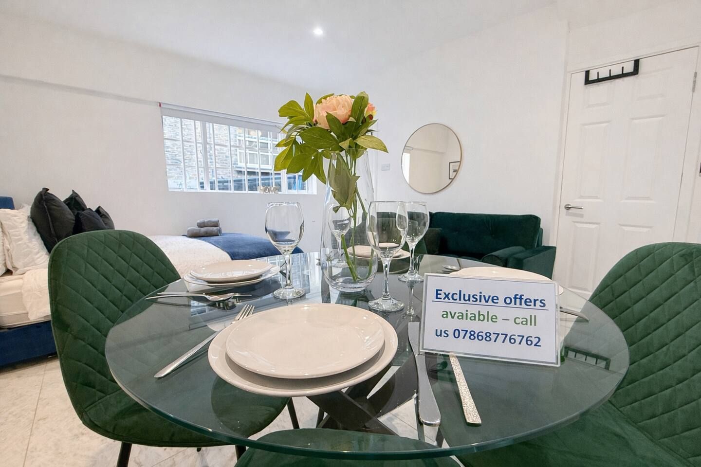 A dining area with a glass table set for four, a vase with flowers, and a sign offering exclusive deals.
