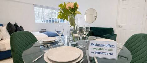 A dining area with a glass table set for four, a vase with flowers, and a sign offering exclusive deals.