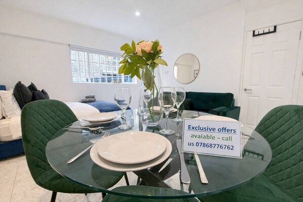 Un comedor con una mesa de vidrio preparada para cuatro, un florero con flores y un cartel que ofrece ofertas exclusivas.