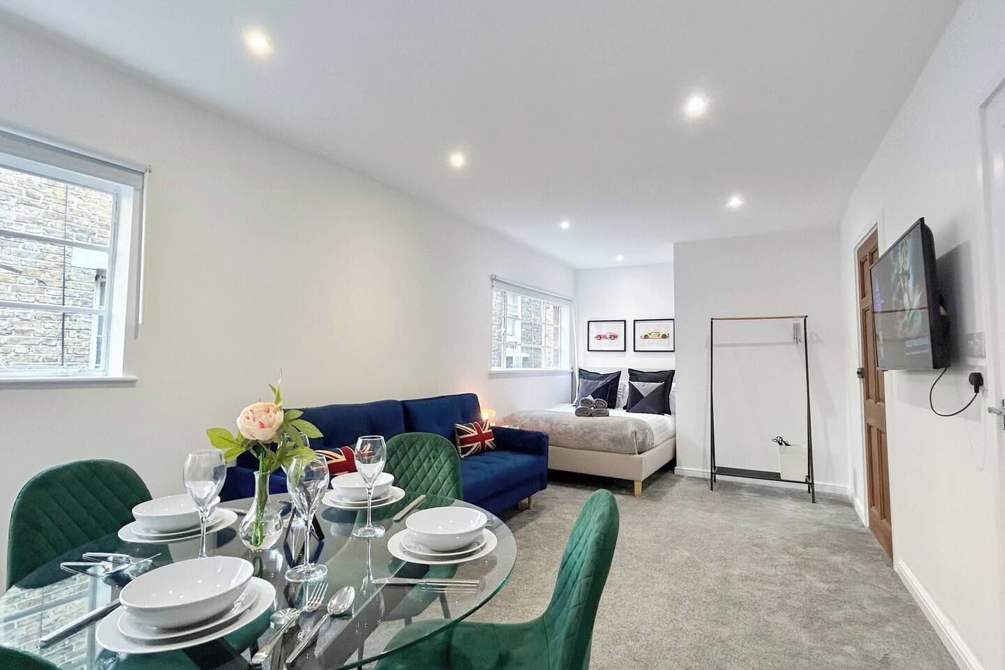 A modern living room with a dining area, a sofa, and a television.