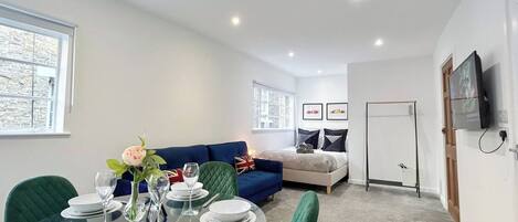 A modern living room with a dining area, a sofa, and a television.