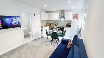 A compact living space with a kitchenette, a dining area, and a seating area with a sofa.