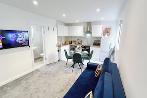 A compact living space with a kitchenette, a dining area, and a seating area with a sofa.