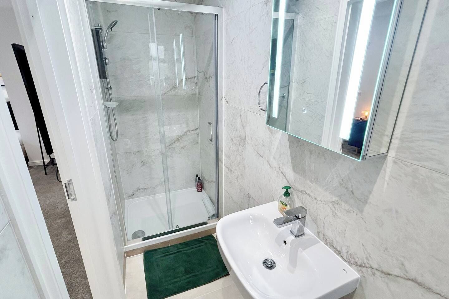 A modern bathroom with a glass-enclosed shower, a white sink, and a mirror above it.