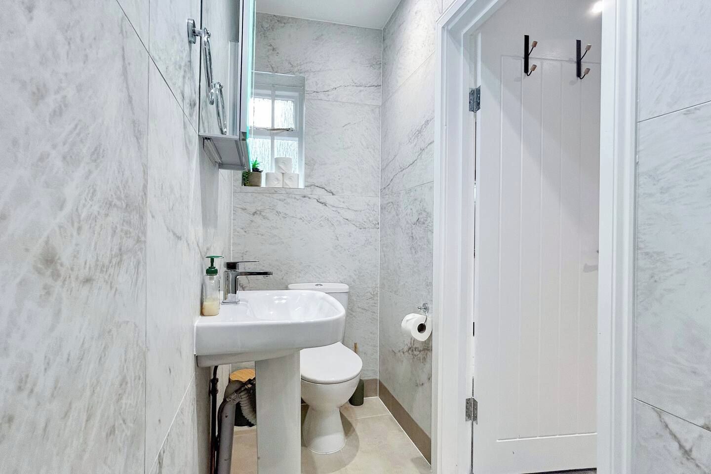 A bathroom with a white sink, toilet, and a door with a handle.