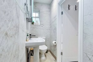 A bathroom with a white sink, toilet, and a door with a handle.