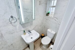 A bathroom with a white sink, a toilet, and a mirror.