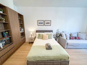 A bedroom with a bed, bedside tables, a wardrobe, a sofa, and two framed pictures on the wall.