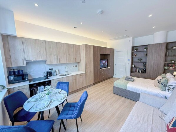 A modern apartment with a dining area, kitchenette, and a living space with a sofa and TV.