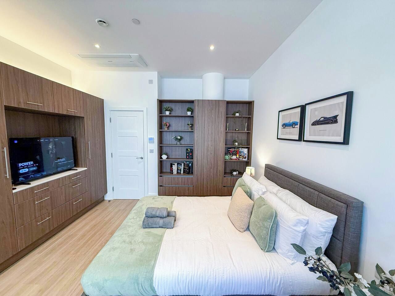 A modern bedroom with a bed, a television, a wardrobe, and a bookshelf.