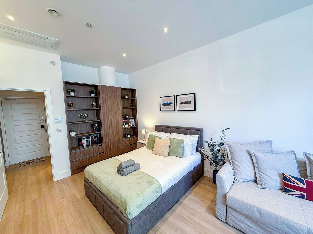 A bedroom with a bed, a sofa, a bookshelf, and a door.