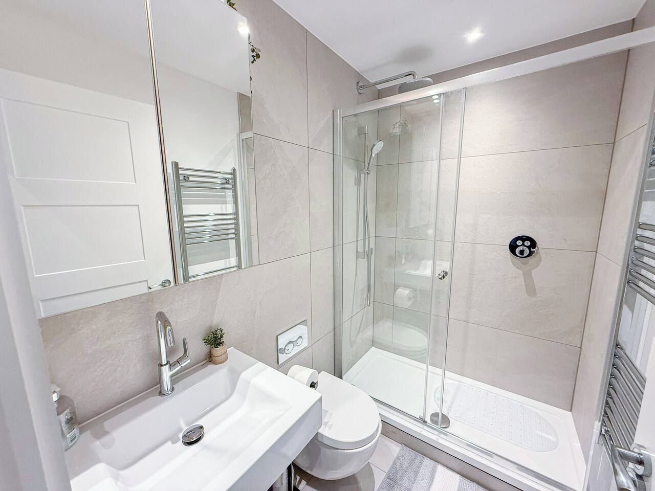A modern bathroom with a glass-enclosed shower, a white sink, and a toilet.