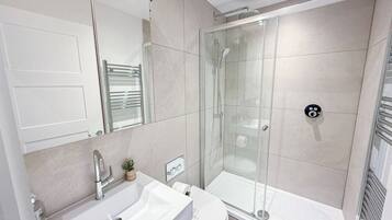 A modern bathroom with a glass-enclosed shower, a white sink, and a toilet.