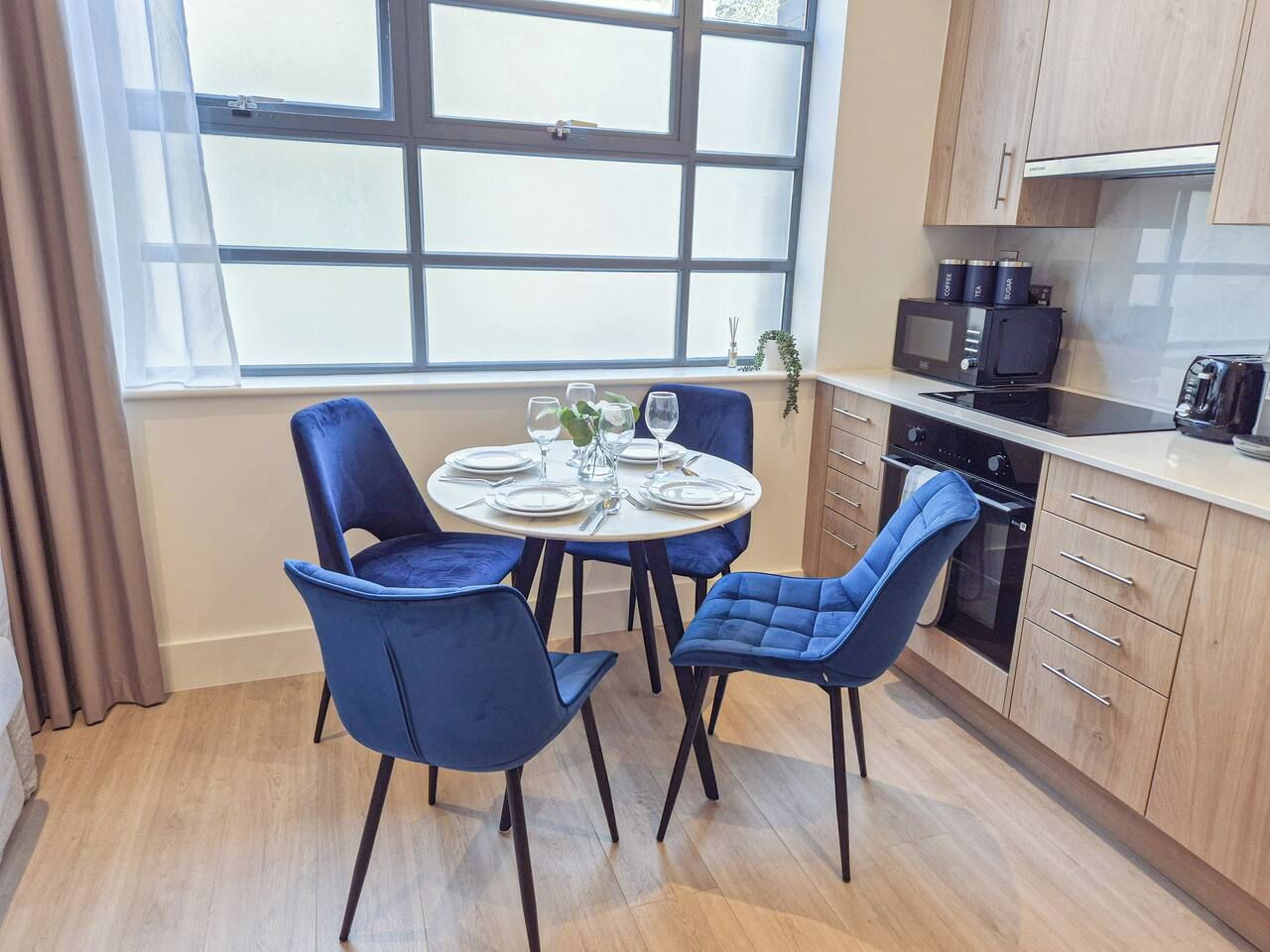 A modern kitchen with a dining table set for two, a microwave, and a stove.
