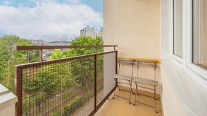 Een balkon met een metalen hekwerk, een tafeltje en een bankje.