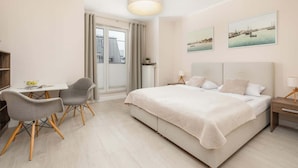Ein Schlafzimmer mit Bett, Nachttisch, Lampe, Stuhl und Schreibtisch mit Sitzgelegenheit.