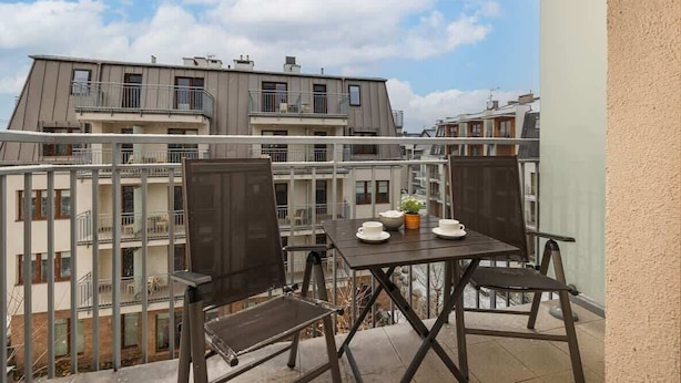 Ein Balkon mit Tisch, Stühlen, einer Topfpflanze und Blick auf Wohnhäuser.