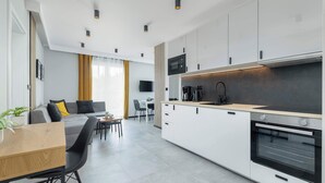 Uma cozinha moderna com armários brancos, forno embutido e uma área de jantar com mesa e cadeiras de madeira.