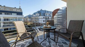 A balcony with a table, chairs, and a view of buildings.