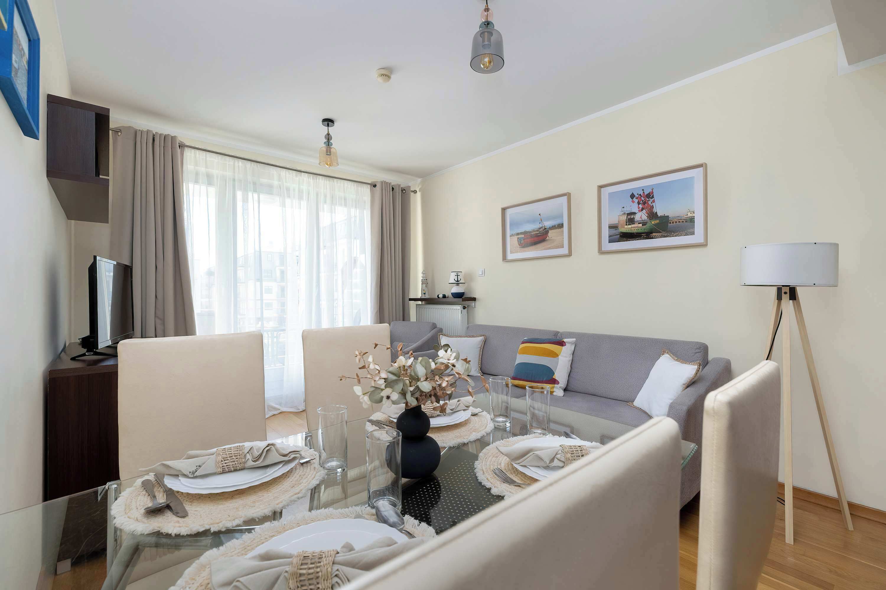 Ein modernes Wohnzimmer mit Essbereich, einer Couch, einem Fernseher und einer Lampe.