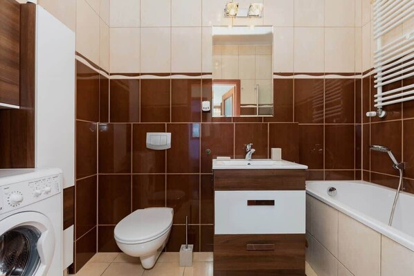 A compact bathroom with a toilet, sink, and bathtub. - Bright Apartment in the Center | Balcony | Bathroom with Bathtub (Świnoujście)