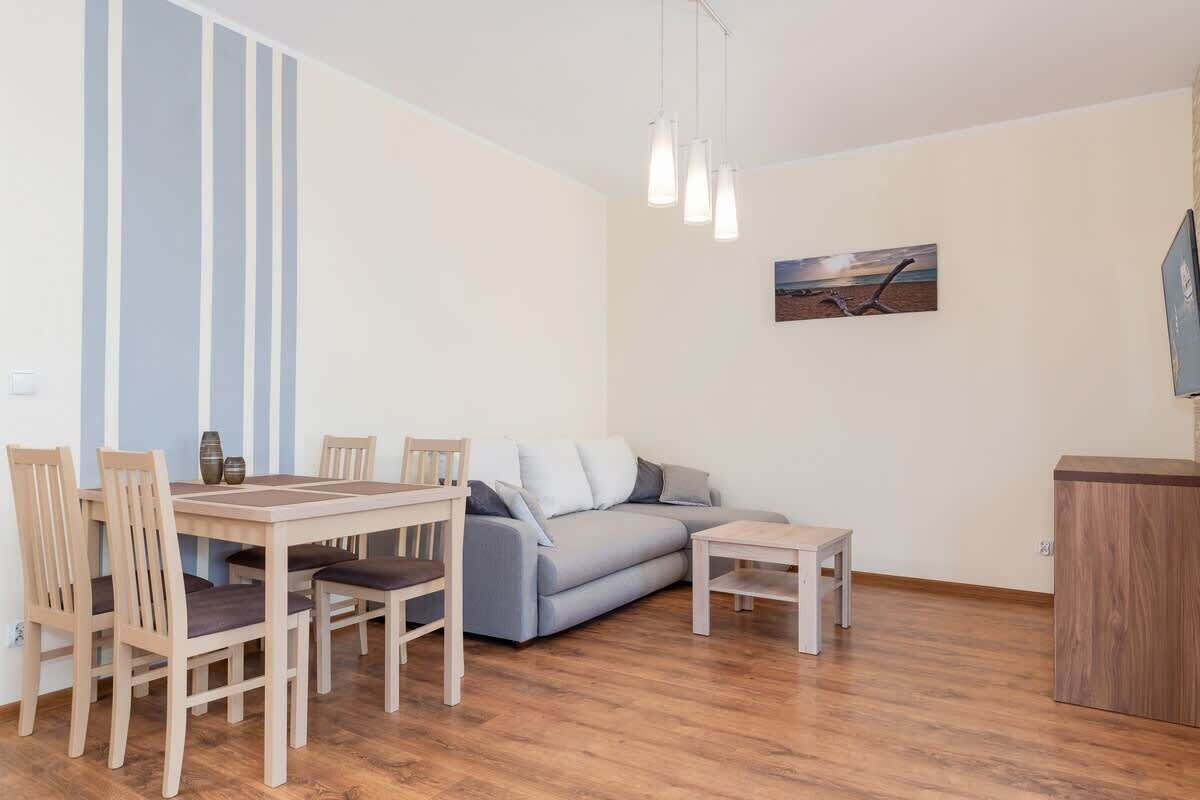 Un salon comprenant un canapé, une table à manger avec des chaises, une petite table et un meuble.