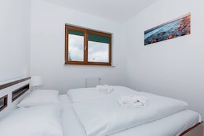 Ein Hotelzimmer mit Bett, Fenster, Gemälde und Heizkörper.