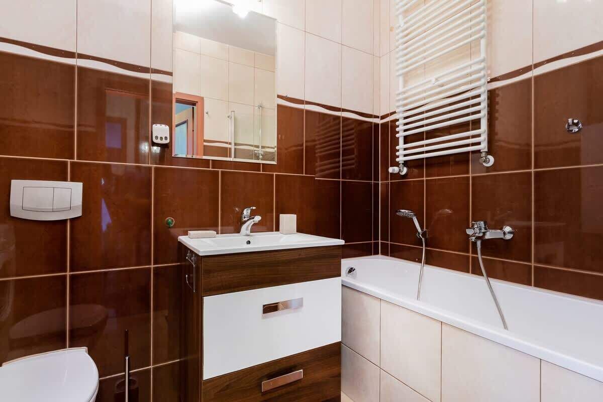 A modern bathroom with a white sink, vanity, and bathtub.