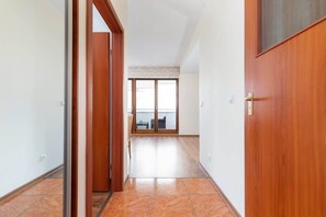 Ein Flur mit Holztür, einer Schiebetür zum Balkon und einem gefliesten Boden.