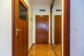 A hallway with wooden doors, a tiled floor, and a small vent on the wall.