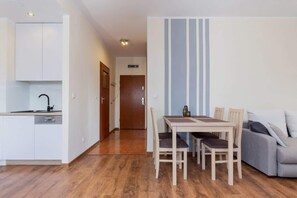 A compact living space with a kitchenette, a dining area with a table and chairs, and a sofa.