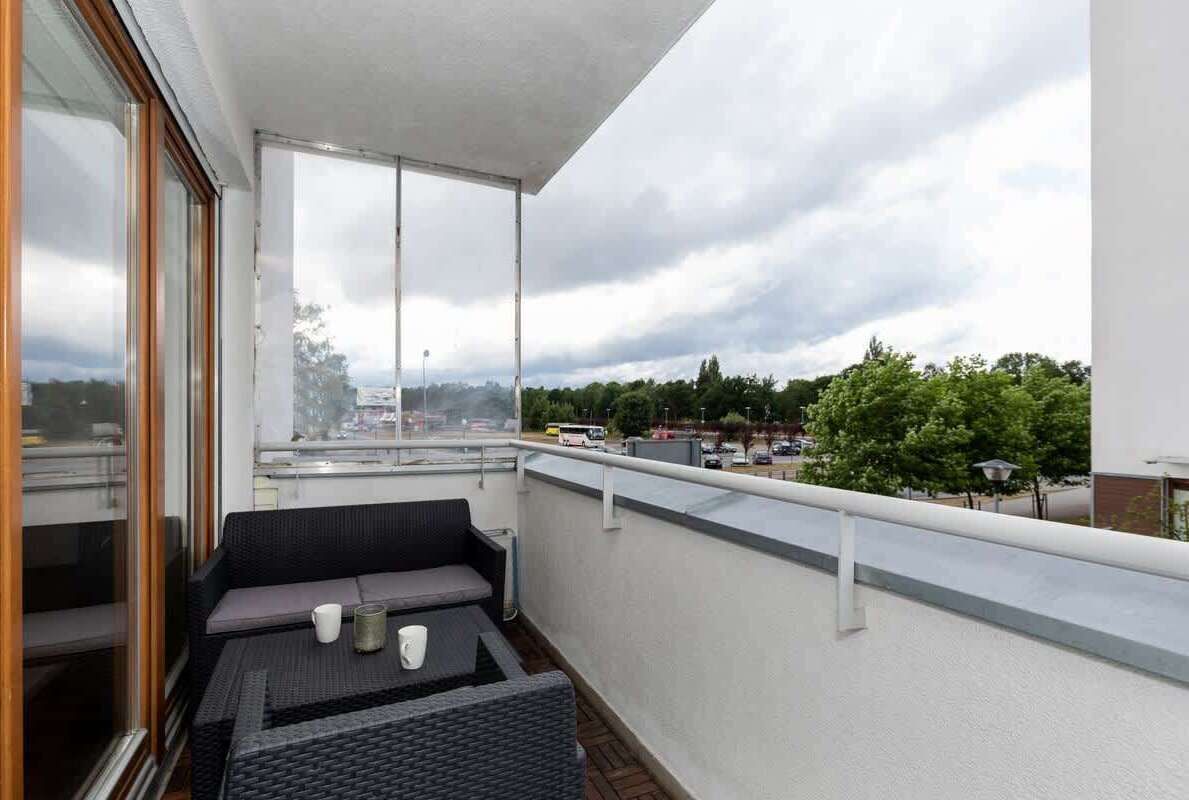 Un balcon avec un canapé et une table, de grandes fenêtres et une vue sur le paysage urbain.