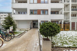 Un immeuble résidentiel à plusieurs étages, doté de balcons, avec un petit arbre au premier plan et des vélos garés à l’extérieur.