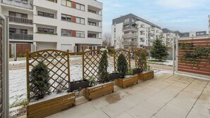 Ein Wohngebäude mit mehreren Balkonen, einem verschlossenen Eingang und einem mit Schnee bedeckten Gelände.