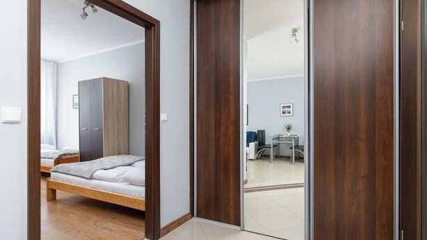 Ein Schlafzimmer mit Bett, Kleiderschrank und einer Schiebetür zu einem Wohnbereich.