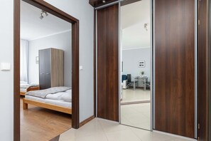 Une chambre à coucher comprenant un lit, une armoire et une porte coulissante donnant sur un espace de vie.