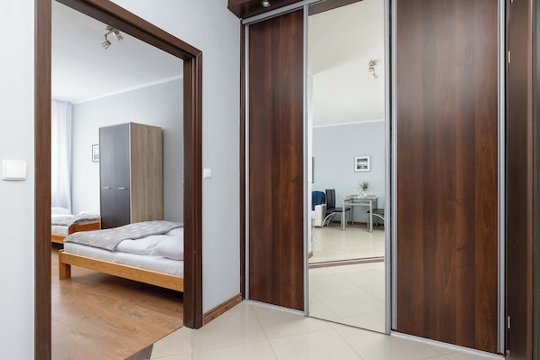 A bedroom with a bed, wardrobe, and a sliding door leading to a living area.