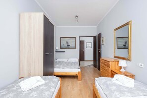 Ein Hotelzimmer mit zwei Betten, einem hölzernen Schminktisch, einem Spiegel und einer Tür zu einem weiteren Raum.