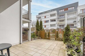 Une cour avec un sol carrelé, une clôture en bois et un bâtiment doté de nombreux balcons et fenêtres.